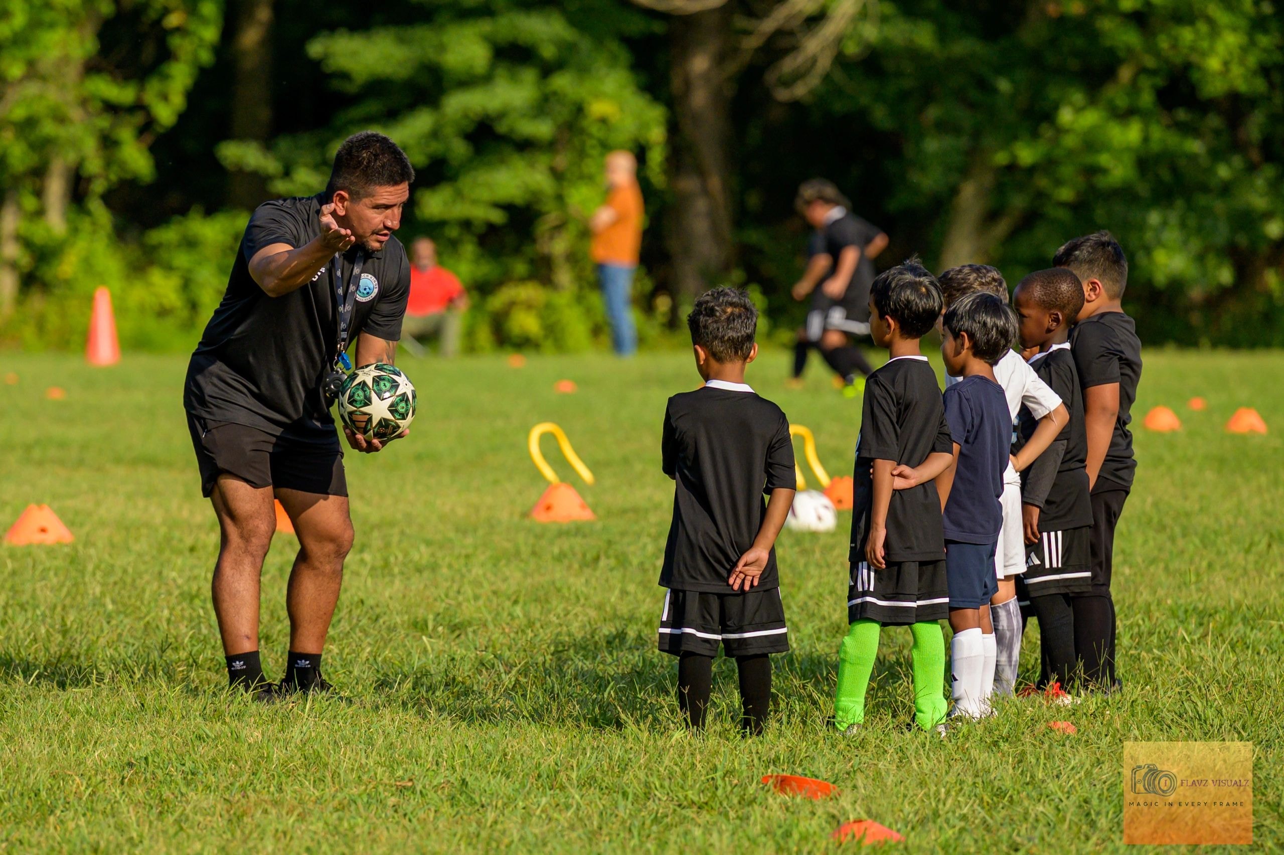 Coach instructing young soccer players at Land of Champions Studio